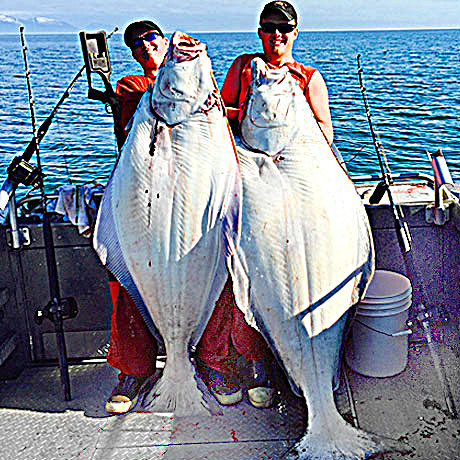 two people holding up big halibut